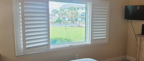 A bedroom with a bed, a TV, and a window with blinds.