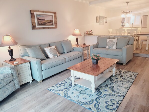A living room with a sofa, a coffee table, a rug, and a dining area with a table and chairs.