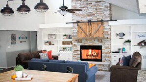 A living room with a fireplace, a stone accent wall, and a ceiling fan.