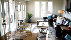 A living room with a wooden coffee table, a brown leather sofa, and a potted plant.