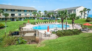 Un hotel con piscina rodeada de sillas de descanso y palmeras.