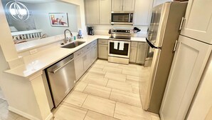 Una cocina moderna con electrodomésticos de acero inoxidable, lavavajillas y microondas.