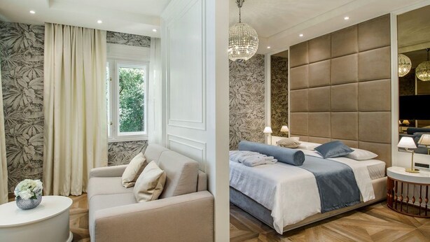 A modern bedroom with a large bed, a sofa, a round side table, and a chandelier. - Miraval Luxury Rooms (Split)