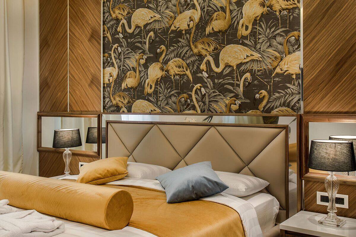 A hotel room with a bed, two bedside tables, and a large wall tapestry.