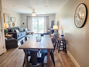 Un salón espacioso con una mesa de comedor de madera, asientos cómodos y un gran reloj de pared.