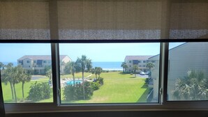 Vista desde una ventana que da a una zona de piscina, un edificio y palmeras.
