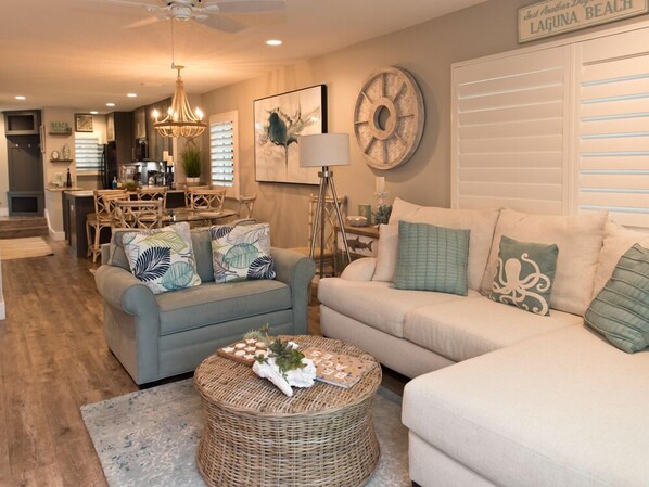 A living room with two sofas, a wicker coffee table, and a dining area with a chandelier. - Watch the ocean from your couch! Townhouse at Summerhouse 161 (ST. AUGUSTINE)