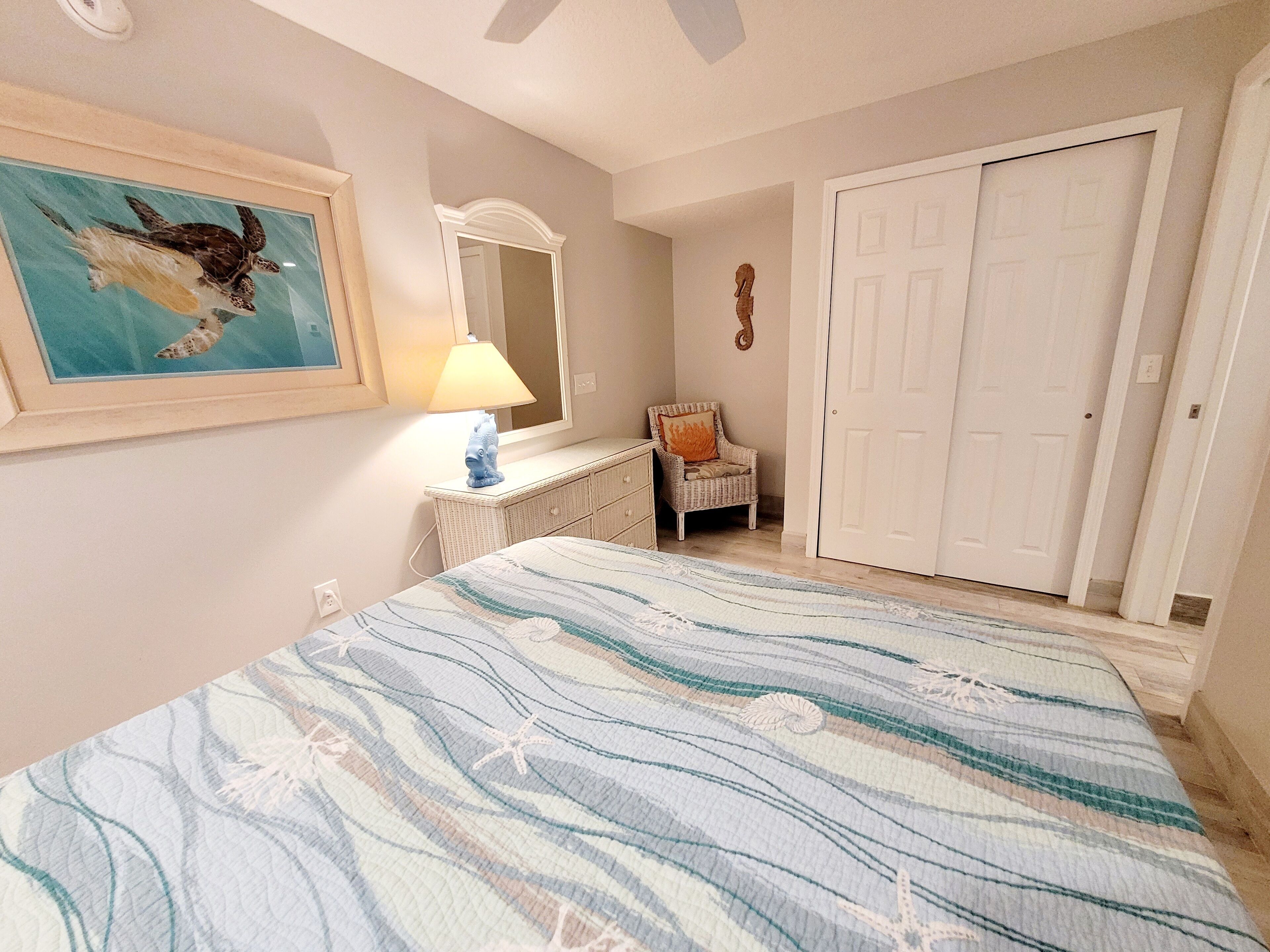 A bedroom with a bed, a dresser, a chair, a mirror, and a door.