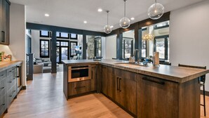 Een moderne keuken met houten kastjes, een groot eiland en hanglampen.