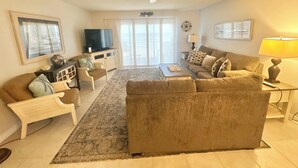 Un salon comprenant un canapé, un fauteuil, une table basse, un téléviseur et un ventilateur de plafond.