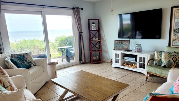 Uma sala de estar com uma grande janela, uma televisão de tela plana e uma mesa de centro de madeira.