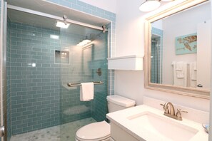 Features a glass-enclosed shower, toilet, and sink with a mirror.