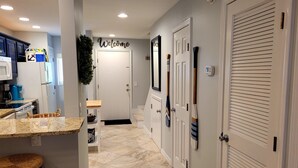 A modern kitchen with a granite countertop, a microwave, and a coffee maker. There is a wicker chair and a small table with a basket. - Oceanfront 2 Bedroom Townhouse Summerhouse 209 (ST. AUGUSTINE)