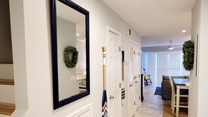 A hallway with white doors, a mirror, and a dining area with a table and chairs. - Oceanfront 2 Bedroom Townhouse Summerhouse 209 (ST. AUGUSTINE)