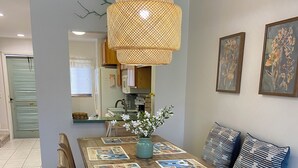 A dining area with a wooden table, blue placemats, and a hanging light fixture.