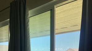 A room with three windows, each with a view of a residential area and a body of water.