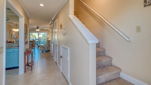 A hallway with a staircase, a kitchen area, and a dining space.