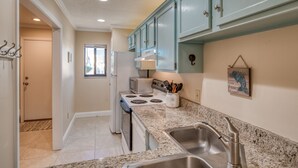 A kitchen with teal cabinets, a granite countertop, a stove, and a sink.
