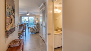 A hallway with a dining area, a ceiling fan, and a view to a balcony.
