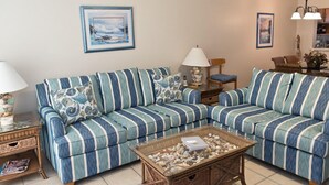 A living room with a striped sofa, a coffee table with decorative stones, a lamp, and framed artwork on the wall.