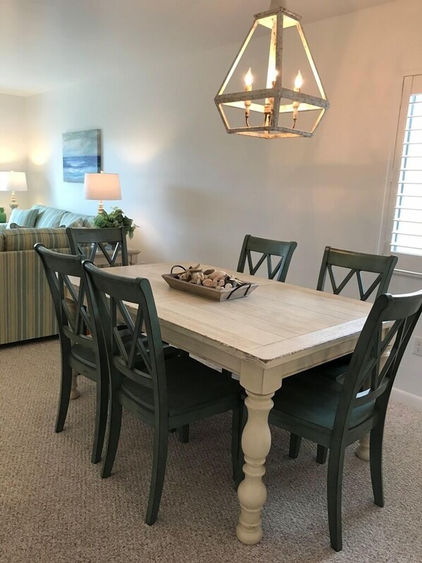 Un coin repas avec une table et des chaises en bois, un luminaire décoratif et un tableau au mur.