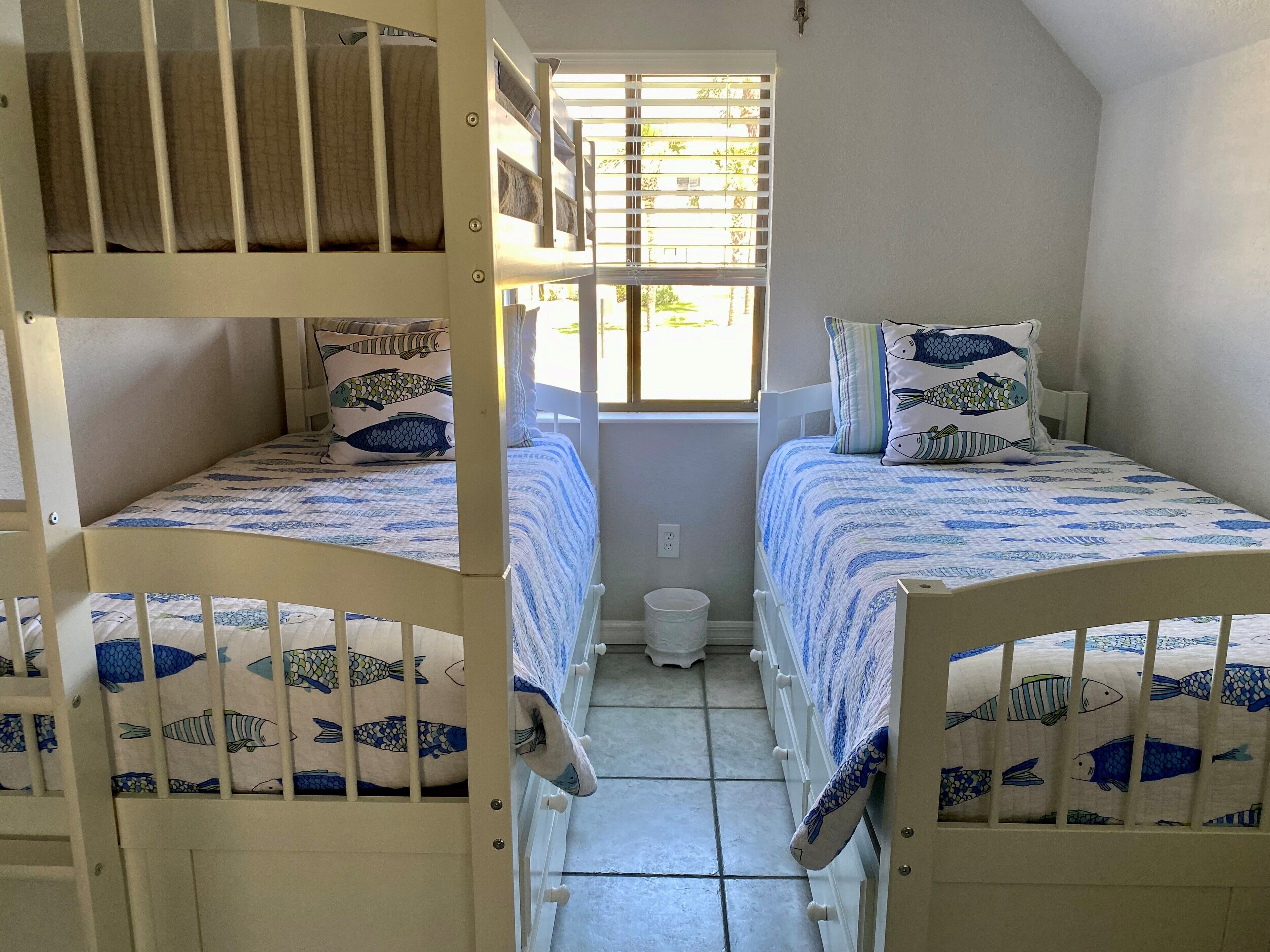 Una habitación con dos literas, cada una con una colcha y almohadas a cuadros de peces.