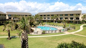 Un hôtel doté d’une piscine entourée de palmiers et de chaises longues.