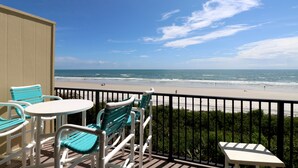 Un balcon avec vue sur la plage, une table et des chaises.