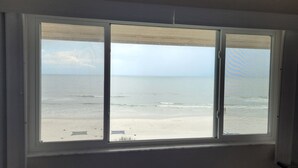 Een kamer met een groot raam dat uitkijkt op een strand.
