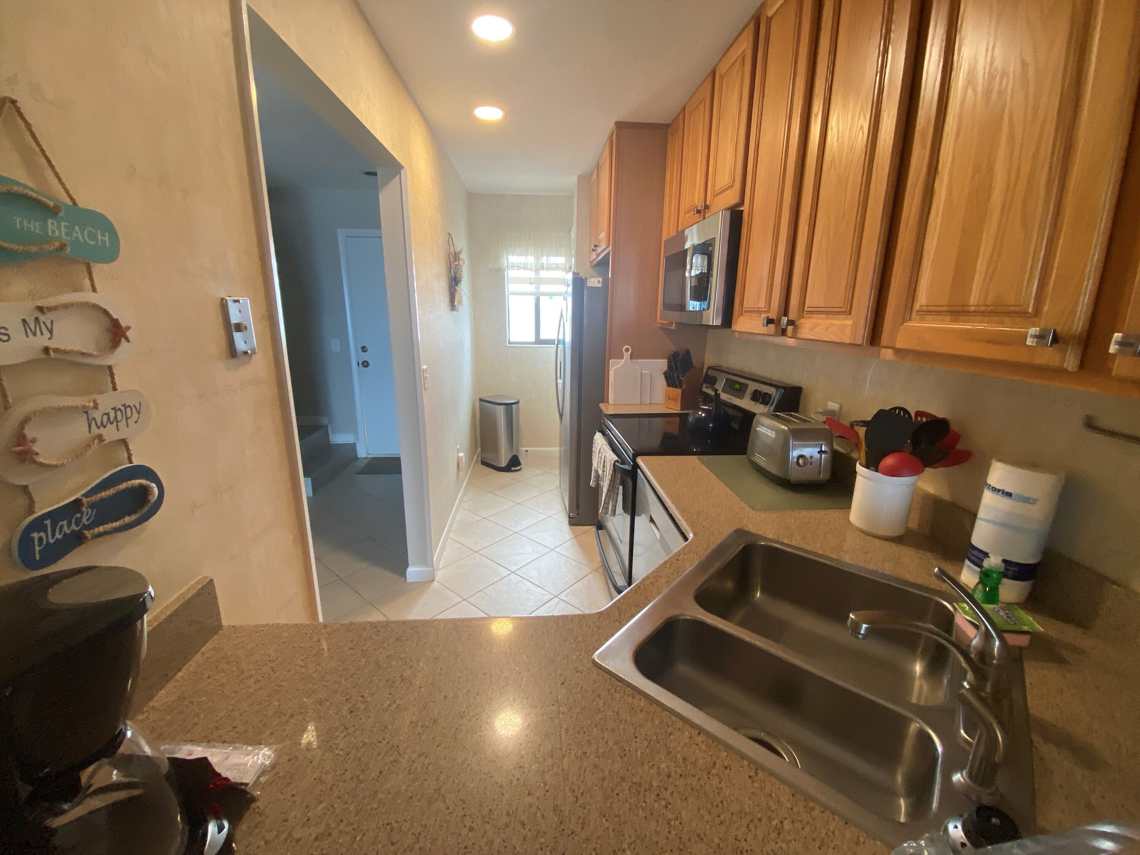 A kitchen with wooden cabinets, a stainless steel sink, a microwave, and a toaster.