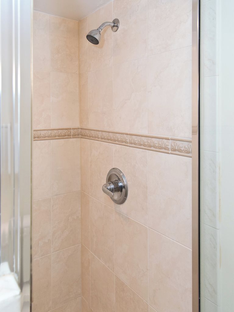 A shower area with beige tiles and a showerhead.