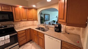 A kitchen with wooden cabinets, a stainless steel sink, a coffee maker, and a dishwasher. - Oceanview 2 Bedroom Flat Summerhouse 319 (ST. AUGUSTINE)