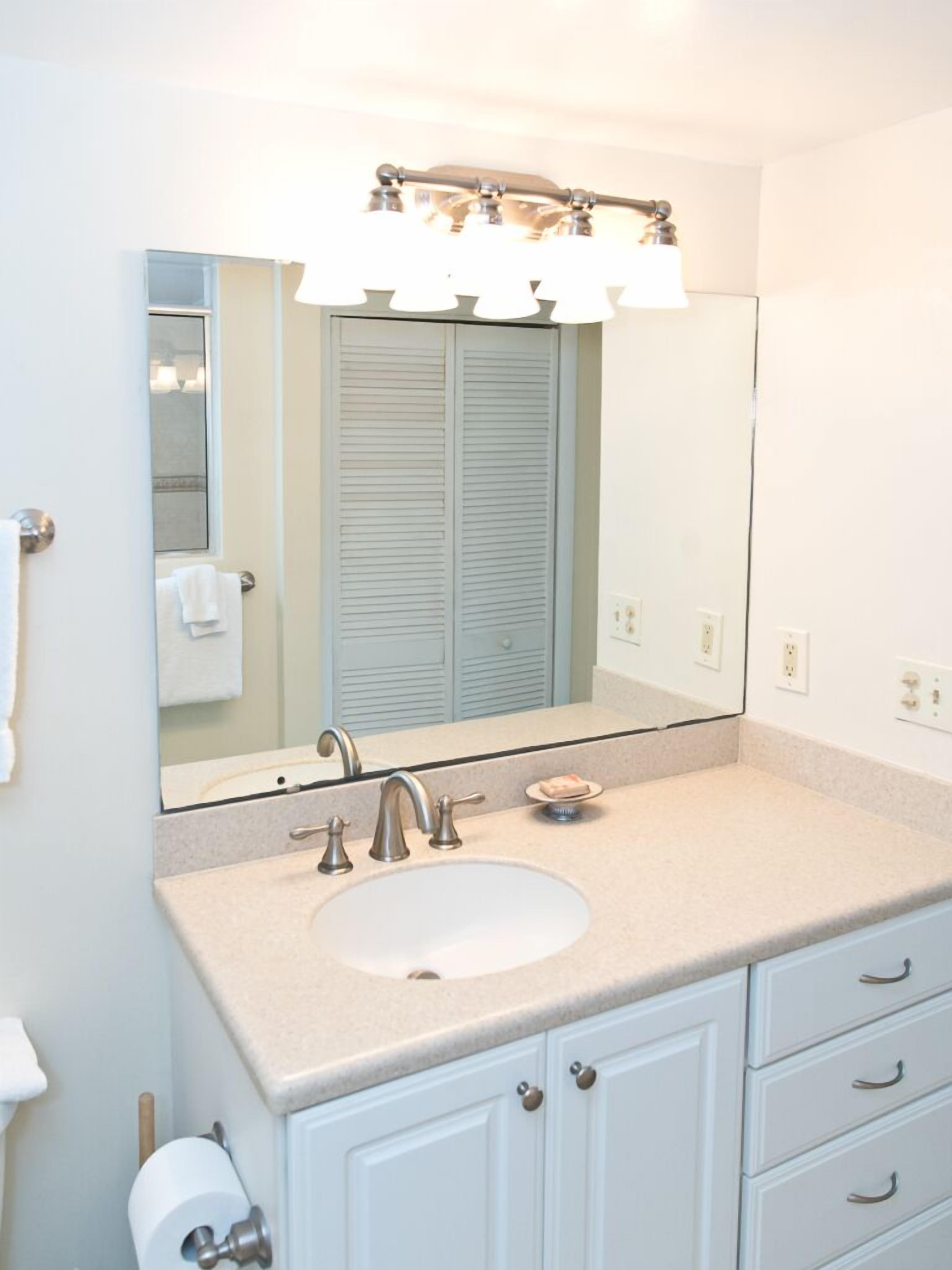 A bathroom with a white sink, a mirror, and a towel rack.