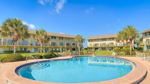 A pool surrounded by a building with multiple balconies, palm trees, and a clear blue sky. - Oceanview 2 Bedroom Townhouse Summerhouse 330 (ST. AUGUSTINE)