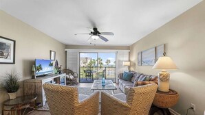 A living room with a television, a ceiling fan, a sofa, and a coffee table. - Oceanview 2 Bedroom Townhouse Summerhouse 330 (ST. AUGUSTINE)