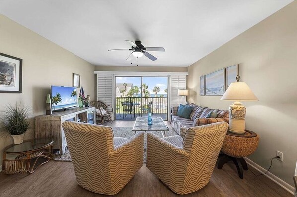 A living room with a television, a ceiling fan, a sofa, and a coffee table. - Oceanview 2 Bedroom Townhouse Summerhouse 330 (ST. AUGUSTINE)