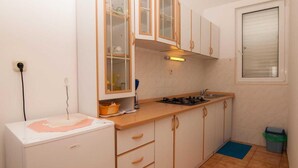 A compact kitchen with white cabinets, a gas stove, and a small refrigerator. - Studios Nina (Split)