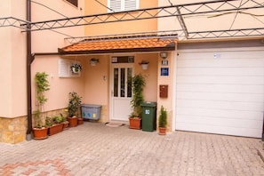 A building entrance with a tiled roof, a door, and several potted plants. - Studios Nina (Split)