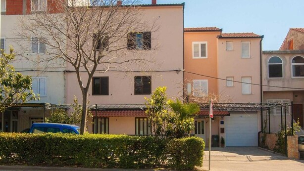 A residential building with a garage, a tree in front, and a clear sky. - Studios Nina (Split)