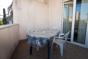 A balcony with a table and two chairs, a sliding glass door, and a view of the cityscape. - Studios Nina (Split)