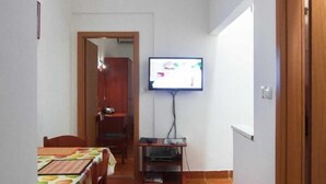 A dining area with a table and chairs, a television mounted on the wall, and a wooden door. - Studios Nina (Split)