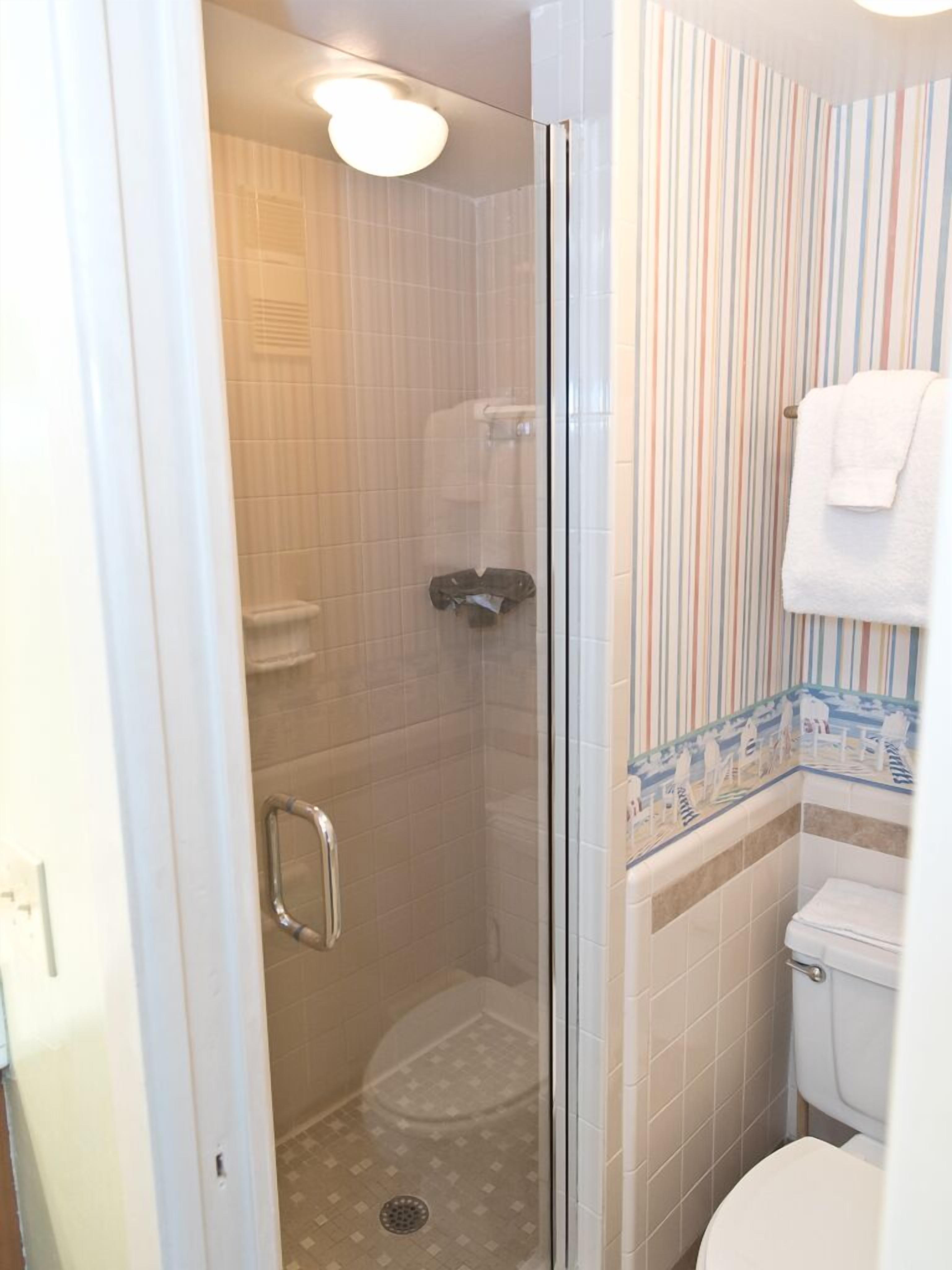 Une salle de bain avec une douche à parois de verre, des toilettes et un porte-serviettes.