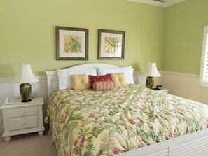 A bedroom with a floral bedspread, two bedside lamps, a nightstand with a phone, and two framed pictures on the wall.