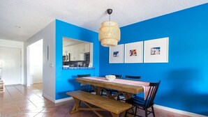 Ein Essbereich mit Holztisch und Bänken, blauen Wänden und einer hängenden Leuchte.