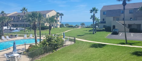 A residential area with a swimming pool, palm trees, and a view of the ocean.