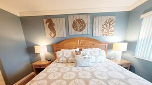 Een slaapkamer met een groot bed, een houten hoofdbord, twee nachtkastjes met lampen en wanddecoratie.