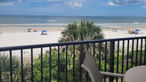 A beach view from a balcony with palm trees, a sandy beach, and umbrellas. - Oceanfront 2 Bedroom Townhouse.  Summerhouse Unit 353 (ST AUGUSTINE)