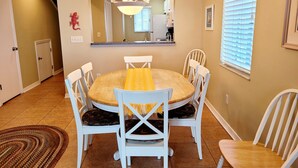 A dining area with a round wooden table, white chairs, a yellow table runner, and a chandelier. - Oceanfront 2 Bedroom Townhouse.  Summerhouse Unit 353 (ST AUGUSTINE)