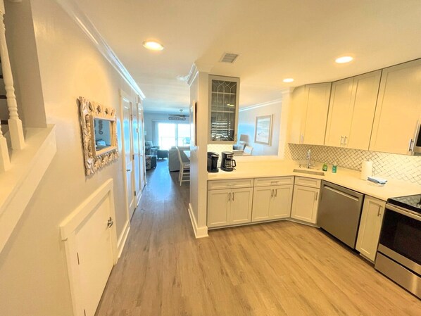 A modern kitchen with white cabinets, a stainless steel oven, and a coffee maker on the counter.