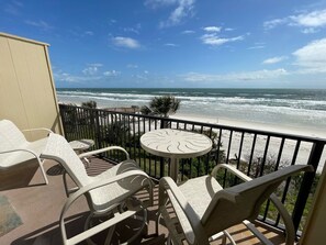 A balcony with a view of the ocean, featuring a table and chairs.